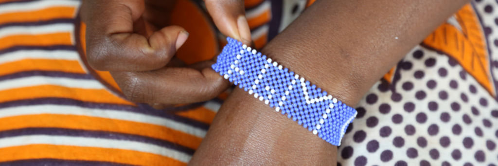 A woman's wrist with a purple bracelet bearing the words "FGM" on it