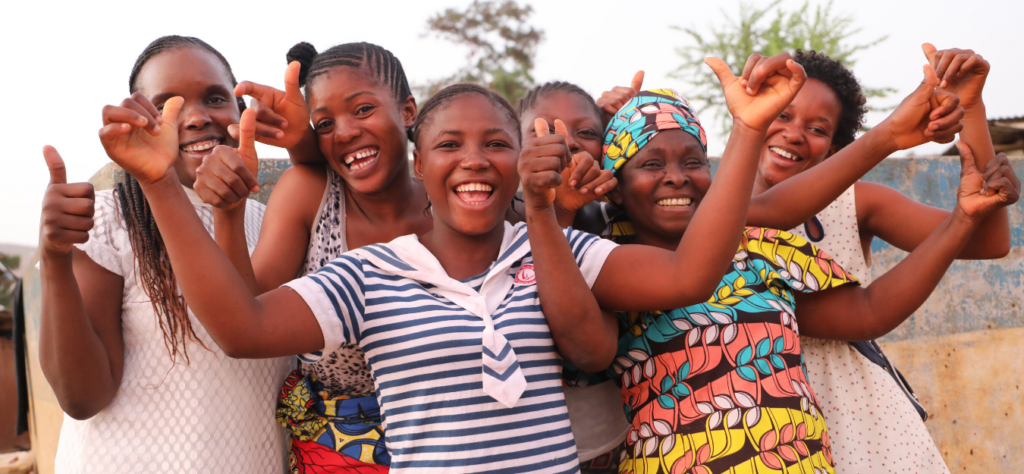 A group of black women and girls smiling with their thumbs up and arms outstretched